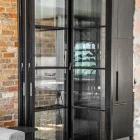 Bifold steel frame glass doors with a black finish, set against a rustic brick wall and modern interior.