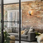 Modern living space featuring a grey sofa with cushions, a dog resting, exposed brick walls, and elegant lighting fixtures.