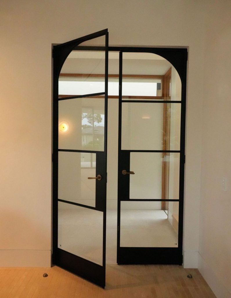 Bespoke black steel double doors with large glass panels, set in a light-coloured room, enhancing the architectural design.