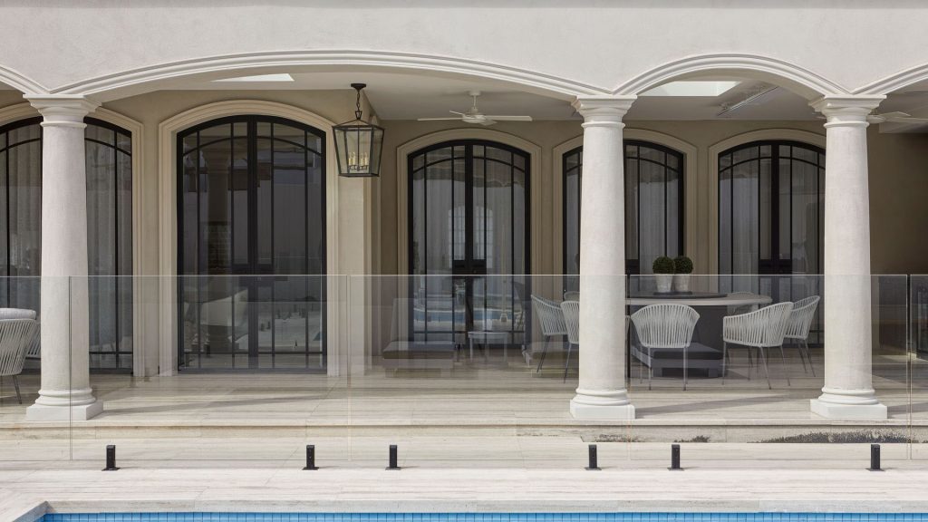 Bespoke architectural steel doors with black frames and arched windows, complementing a modern outdoor terrace and pool area.