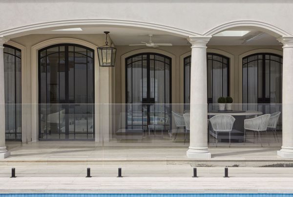 Bespoke architectural steel doors with black frames and arched windows, complementing a modern outdoor terrace and pool area.