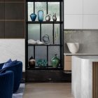 A stylish interior showcasing a black-framed display with decorative vases and sculptures beside a marble kitchen island.