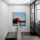 Brightly lit stairwell featuring a circular skylight, modern glass panels, and a vibrant abstract painting on a light-coloured wall.
