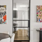 Steel-framed glass sliding door in a modern interior, featuring a minimalist design with light wood flooring and contemporary art.