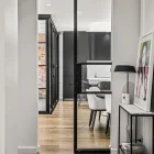 Internal view featuring a sleek steel-framed glass sliding door, with a modern hallway leading to a stylish kitchen area.