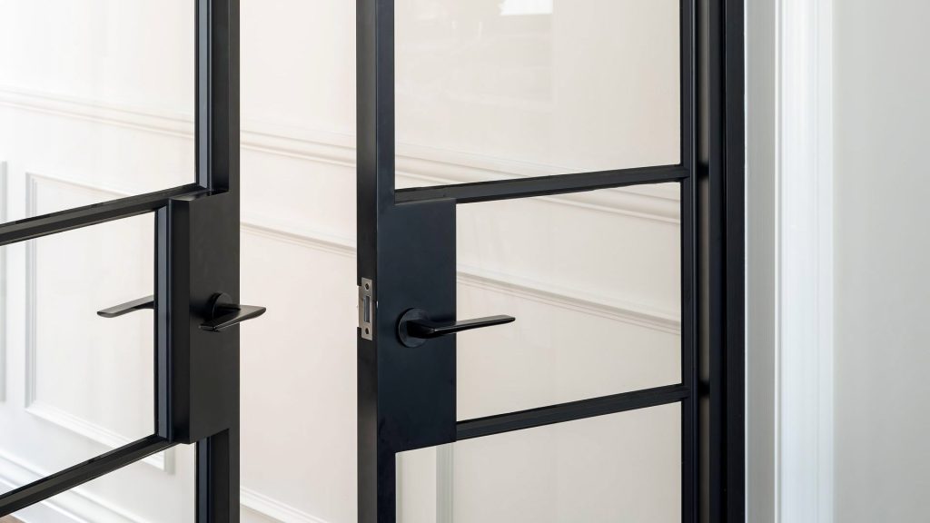Bespoke black steel-framed doors with sleek glass panels, set against a neutral wall featuring elegant moulding.