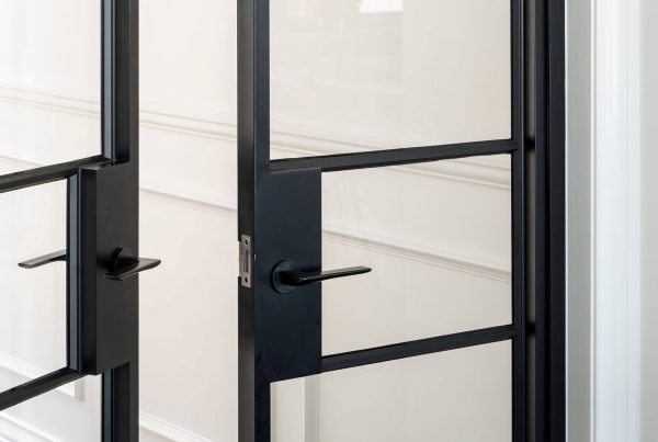 Bespoke black steel-framed doors with sleek glass panels, set against a neutral wall featuring elegant moulding.
