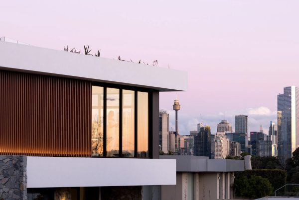 Modern residence featuring sleek architectural lines, large glass windows, and wooden accents, set against a city skyline at dusk.