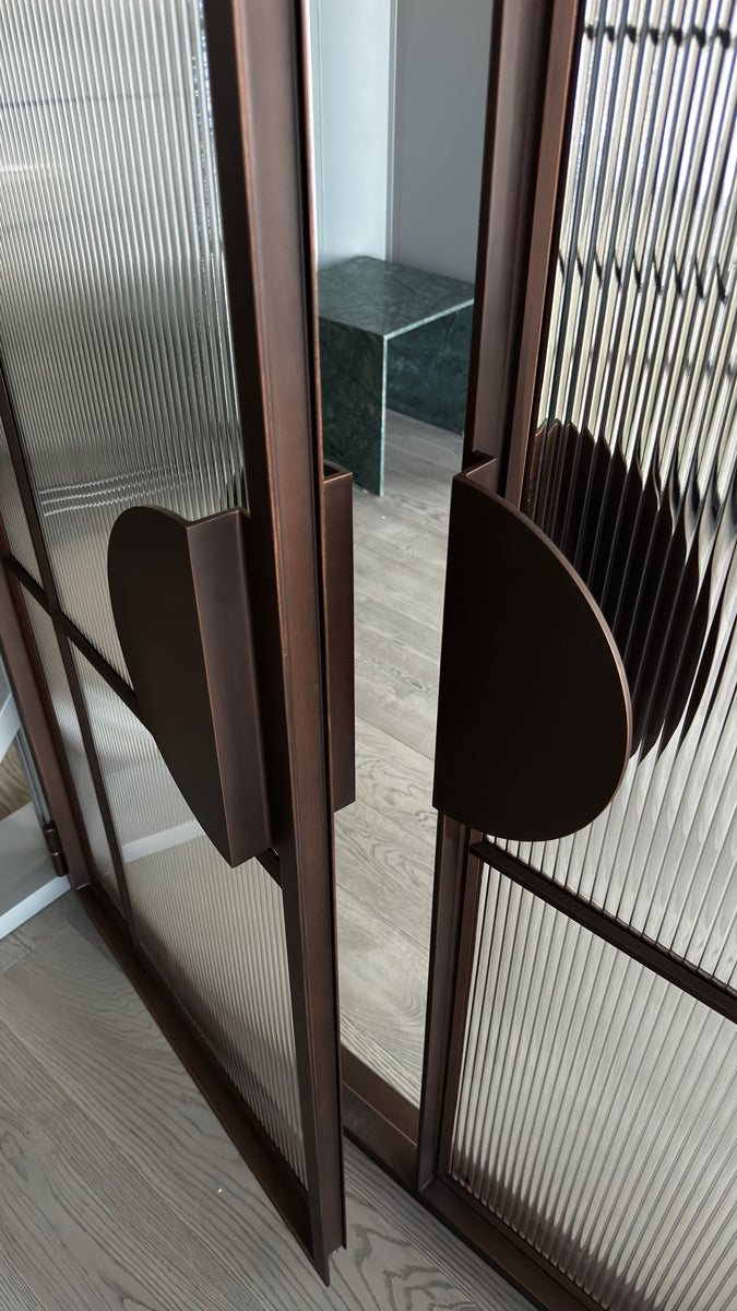 Stylish dual glass hinge doors with bronze frames and textured panels, showcasing a contemporary design that complements modern interiors.