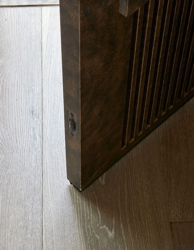 Close-up of a bespoke steel door corner with a textured finish, set against a light wood floor, highlighting craftsmanship and design.