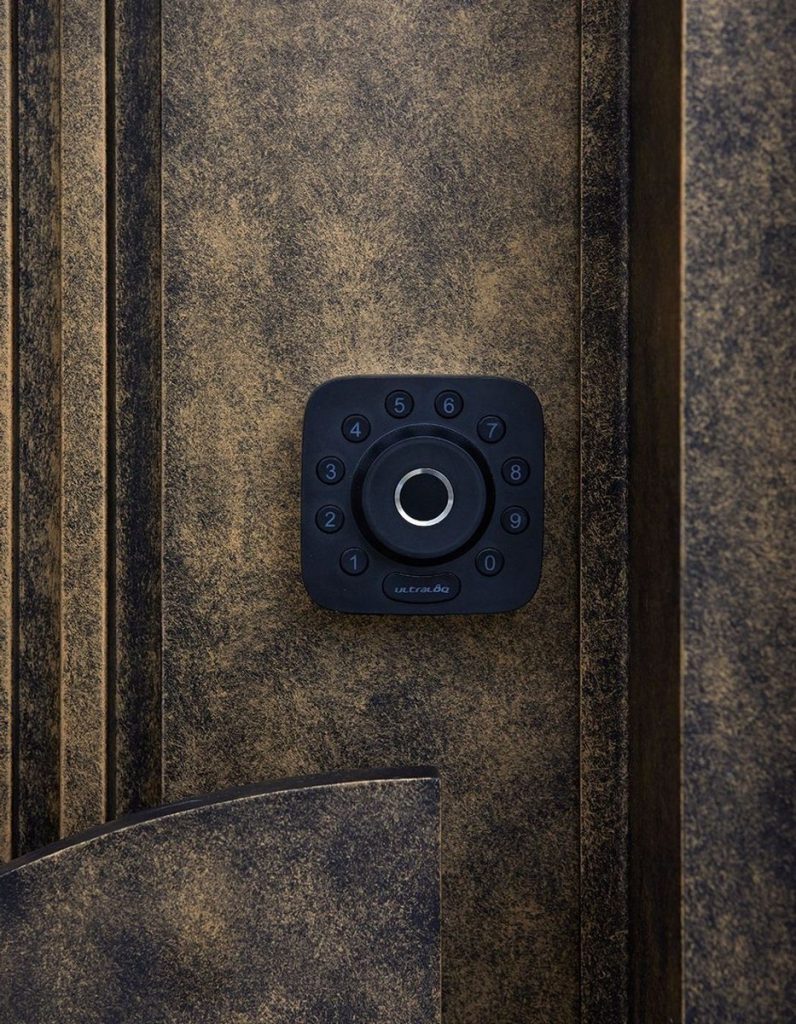 Close-up of a black keypad lock mounted on a textured bronze door surface, highlighting modern security design.