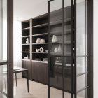 Bespoke steel-framed glass door leading to a modern interior with dark wooden shelves displaying white ceramics and books.