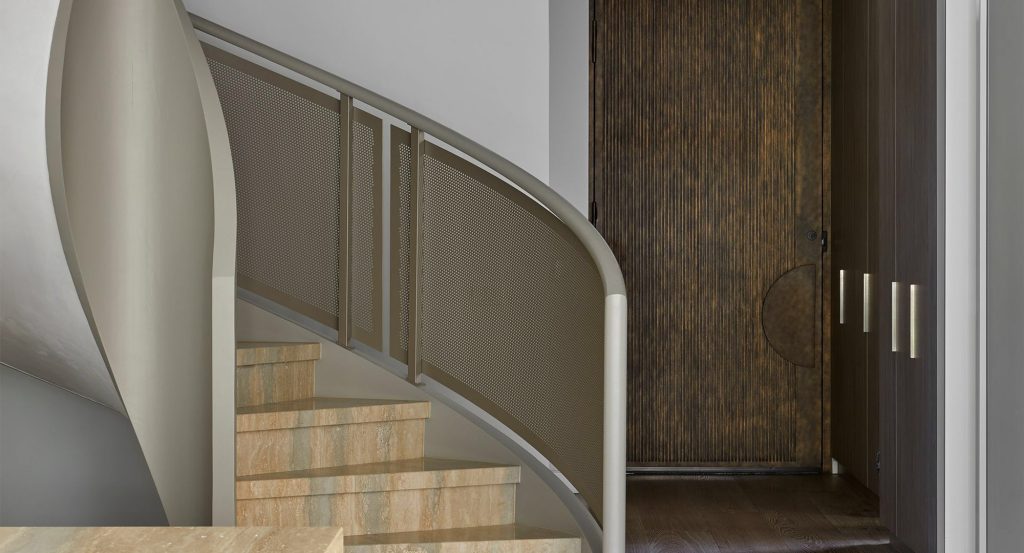 Curved staircase leading to a textured wooden door; contemporary design with neutral tones and sleek metal details.