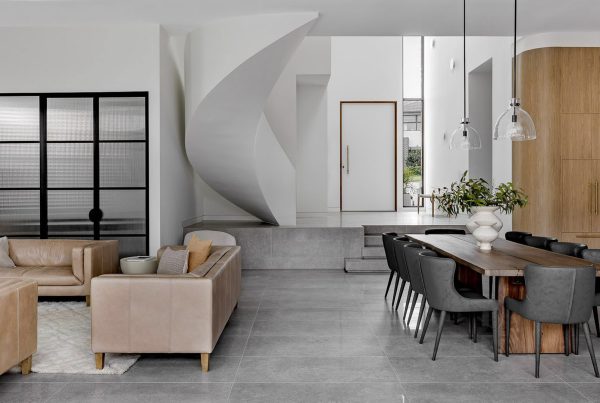 Modern open-plan living area featuring a spiral staircase, stylish beige sofas, a wood dining table, and large steel-framed windows.
