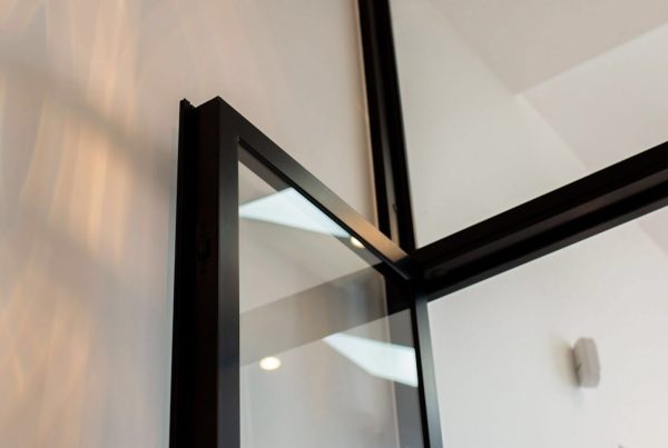 Close-up of a sleek black steel-framed glass door, showcasing clean lines and modern design against a softly lit interior.