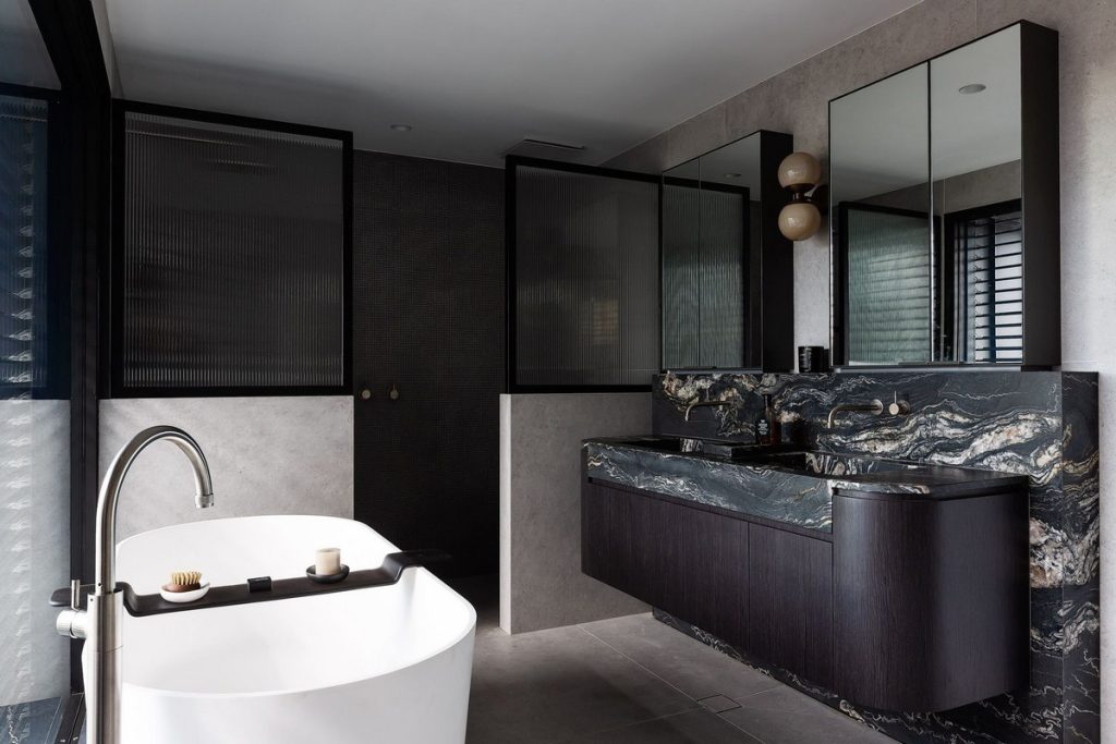 Luxurious bathroom featuring a freestanding white bathtub, elegant black cabinetry, and striking dark marble surfaces. Modern, minimalistic design.