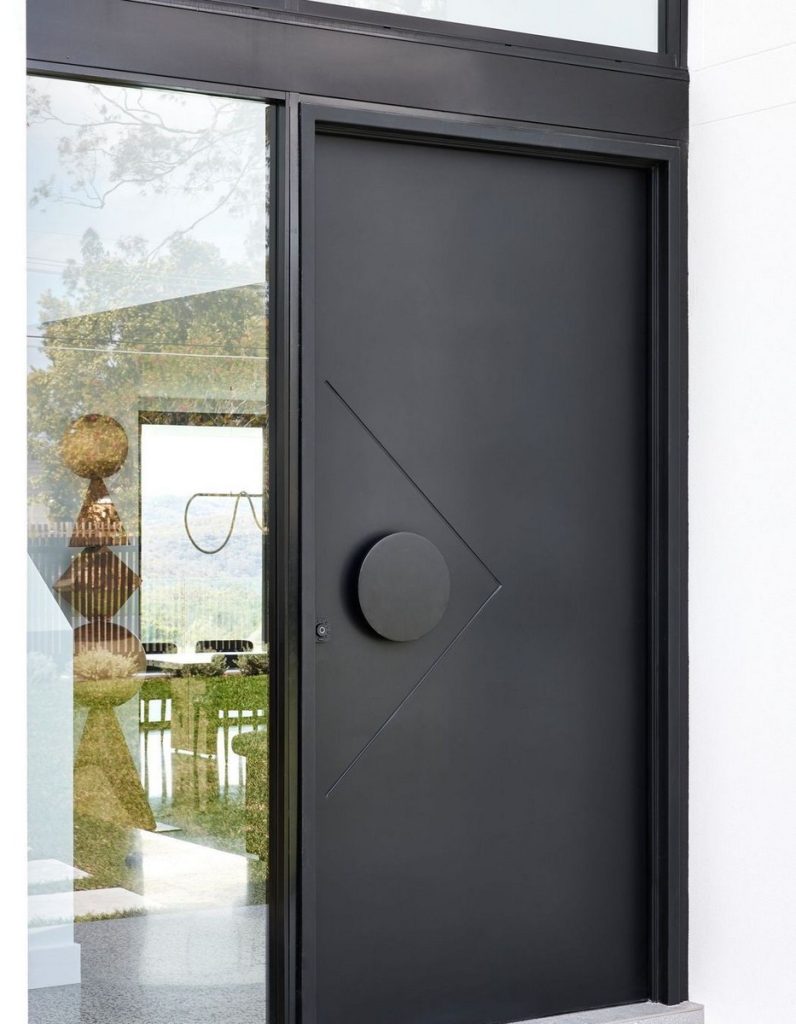 Sleek black steel door featuring a circular handle and angular design, framed by large glass panels showcasing a blurred interior.