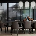 Contemporary dining area featuring a dark wooden table, upholstered chairs, and glass-panelled partitions with a textured finish.