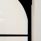Black steel-framed glass door with an elegant arch design, set against a minimalist white wall, highlighting modern architectural style.