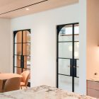 Elegant steel frame glass hinge doors in a modern interior, featuring a marble island and soft-toned furnishings, enhancing the space's design.