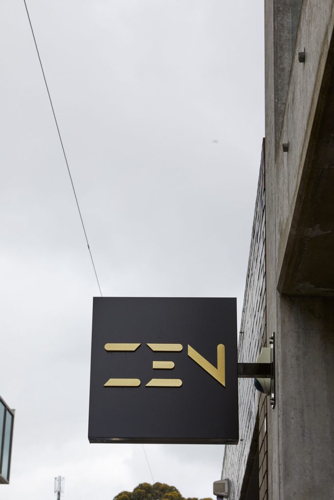 Zen Doors & Windows Showroom Signage - Architectural Design Excellence Signage for Zen Doors & Windows featuring a modern black square with gold lettering spelling 'ZEN', attached to a contemporary building.