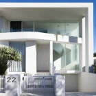 Modern white architectural entrance with curved glass balcony, spiral staircase, and tropical plants in a minimalist style.