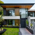 Modern two-storey house featuring large glass panels, wooden accents, and a landscaped garden with succulents and a stone pathway.