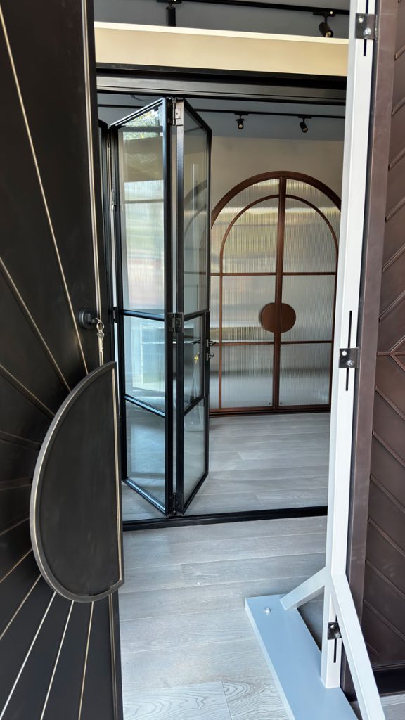 Bespoke Steel Door Showroom - Custom Architectural Designs Display of bespoke architectural steel doors, featuring a black entry door and a glass frame door, set in a modern showroom layout.
