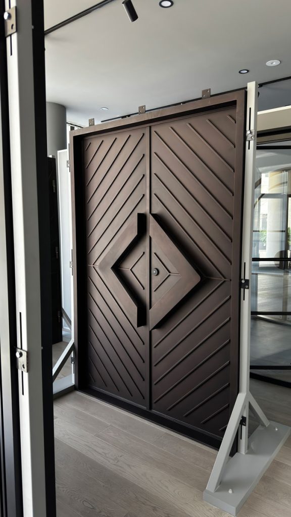Bespoke Steel Entrance Door Design Showcased at Zen Doors & Windows Bespoke steel entrance door with a geometric, diamond-shaped design, set in a modern showroom with natural light and neutral tones.