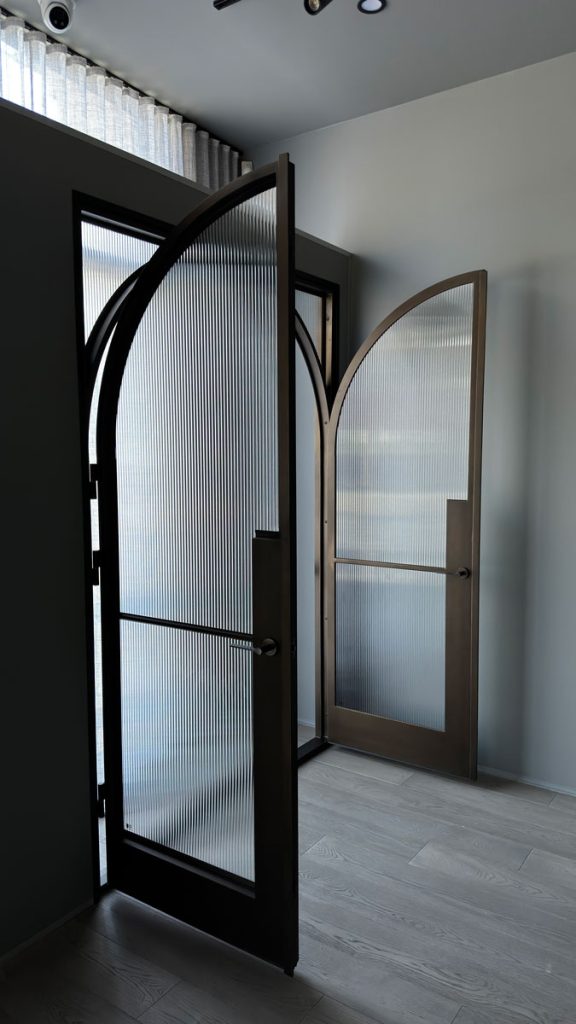 Bespoke Steel Door Showcase - Zen Doors & Windows Bespoke steel doors with arched designs and textured glass, set in a light grey interior with smooth wooden flooring.