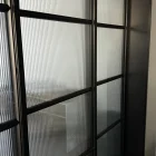 Black steel frame sliding doors with ribbed glass panels, showcasing a modern design suitable for residential and commercial spaces.