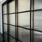 Steel-framed sliding doors with ribbed glass panels, featuring a sleek black finish, set within a modern interior space.