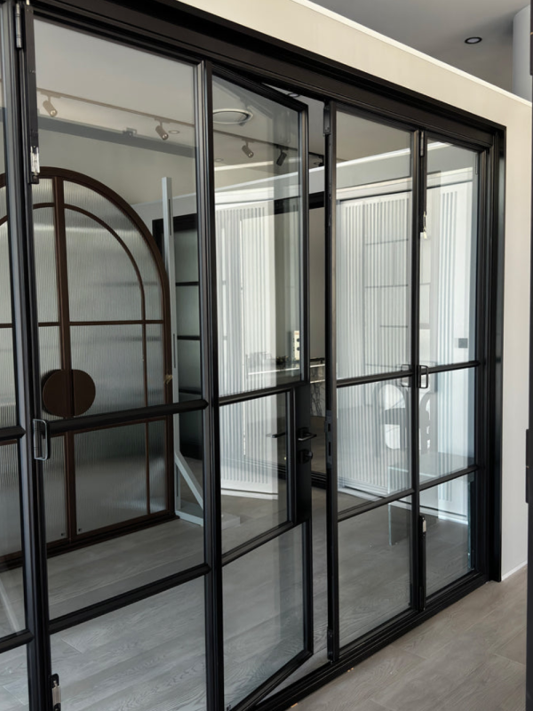 Bifold steel-framed glass doors in a modern interior, featuring a sleek black profile and contemporary design elements.