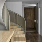 Curved staircase leading to a wooden door, featuring warm wood tones, sleek grey walls, and a minimalist design aesthetic.
