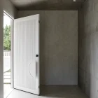 Bespoke white battened entry door partially open in a modern, minimalist space with concrete and wooden flooring.
