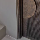 Close-up of a galvanised iron entry door featuring a round handle, textured panel lines, and a minimalist grey backdrop.