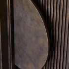 Stylish iron batten hinge with a sleek, curved design, set against a backdrop of textured vertical lines in a rich, dark finish.