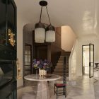 Elegant entryway featuring a round stone table with floral arrangement, dramatic pendant lights, and a staircase enhancing the modern aesthetic.