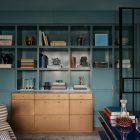 Stylish interior featuring a teal shelving unit with books and decorative objects, complemented by a sleek bronze cabinet and dark glass accents.