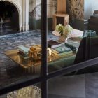 A stylish interior featuring a marble fireplace, elegant furniture, and a coffee table stacked with books, surrounded by floral wallpaper.